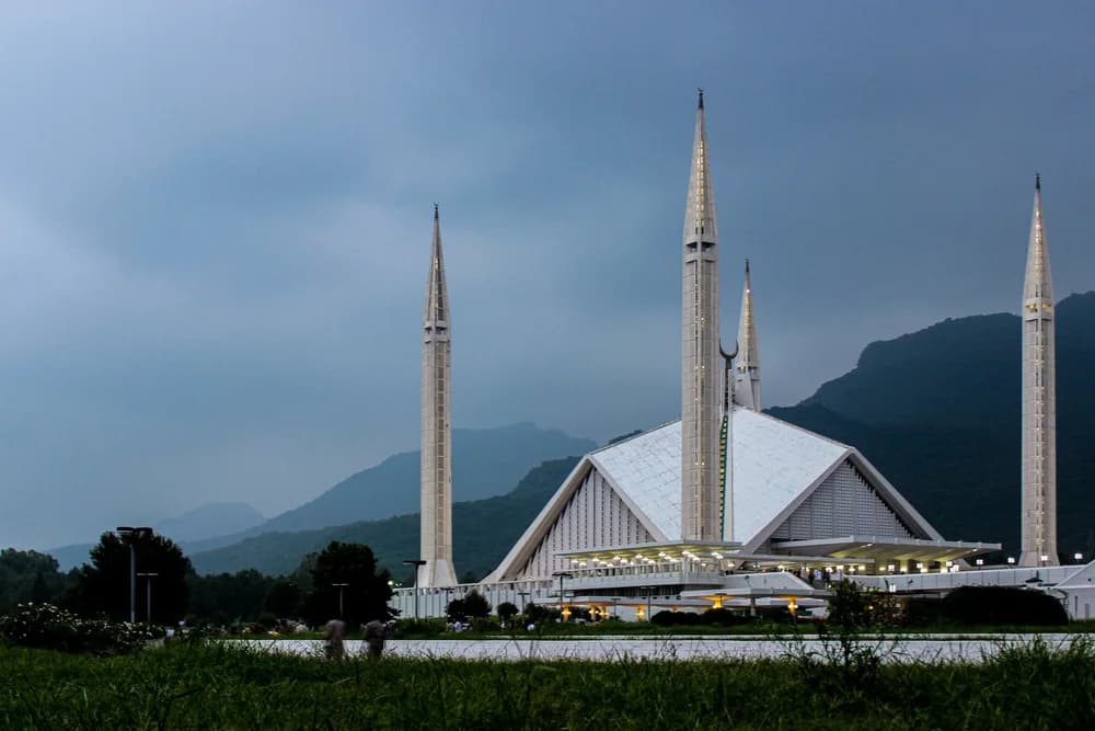 Faisal Mosque in Islamabad beneath the Margalla Hills at dusk